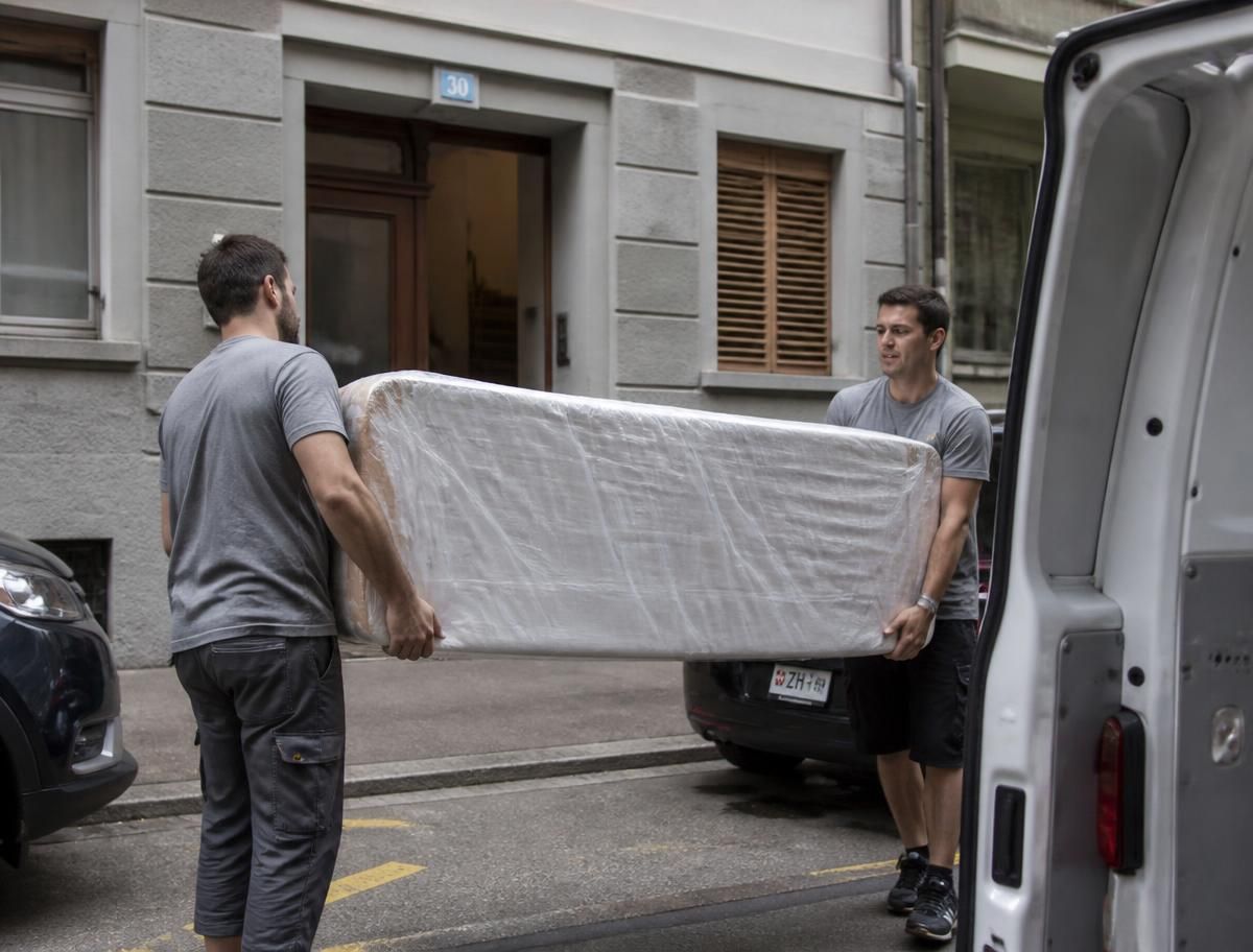 Zwei Mitarbeiter verladen aussortierte Gegenstände in einen Transporter
